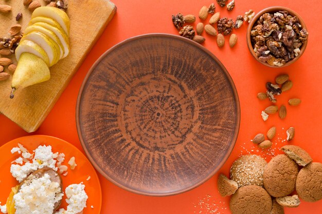 Foto concepto de desayuno, dieta y desintoxicación saludable - cuenco sobre tablero de madera, frutas, requesón, nueces y galletas de avena alrededor sobre fondo brillante. naturaleza muerta, endecha plana, vista superior, espacio de copia