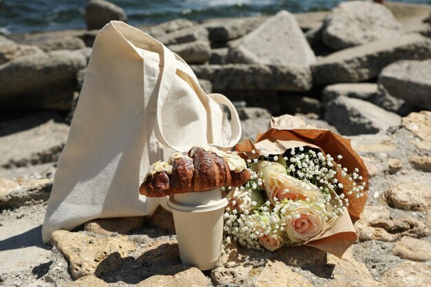 Concepto de desayuno increíble cerca del mar con croissant y vaso de bebida de papel