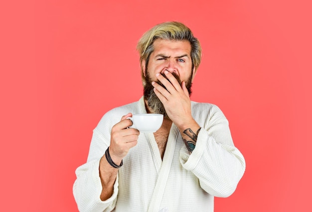 Concepto de desayuno La mañana comienza con café Comprensión de sus ritmos diarios Hombre con barba en bata de baño disfruta del café de la mañana Chico con ropa doméstica sostiene una taza de café Hombre barbudo con taza