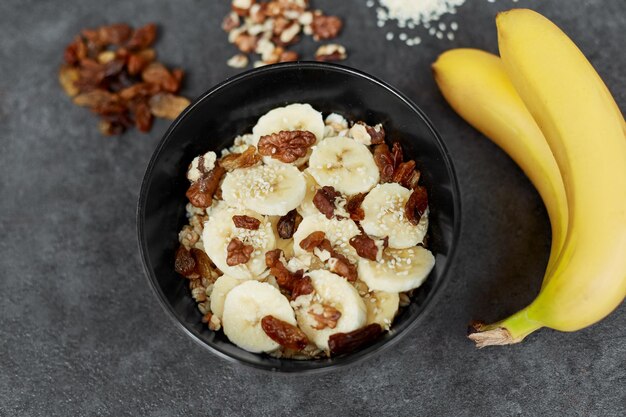 Concepto de desayuno saludable con avena, avena con plátanos, nueces, pasas, semillas de sésamo