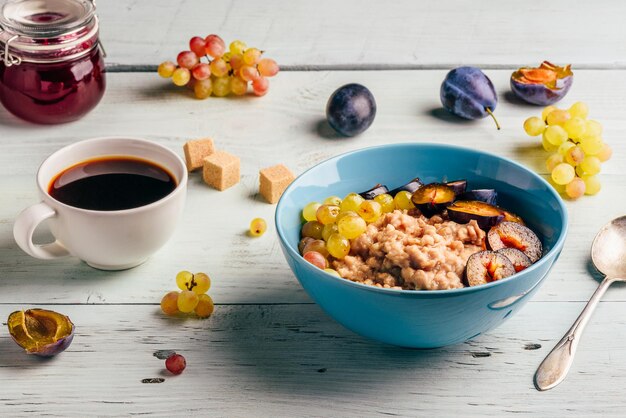 Concepto de desayuno saludable Gachas de avena con uvas verdes frescas de ciruela y taza de café