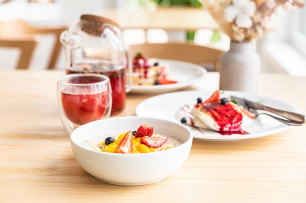 Concepto de desayuno saludable con té de hierbas, gachas de avena, requesón, buñuelos y panqueques