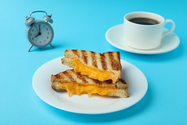 Concepto de desayuno con sándwiches a la parrilla sobre fondo azul.