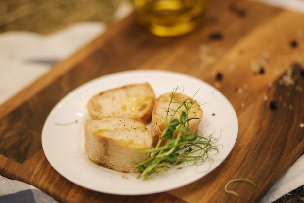 Concepto de desayuno vegano saludable pan integral con aceite de oliva baguette en rodajas en heno de mesa de madera