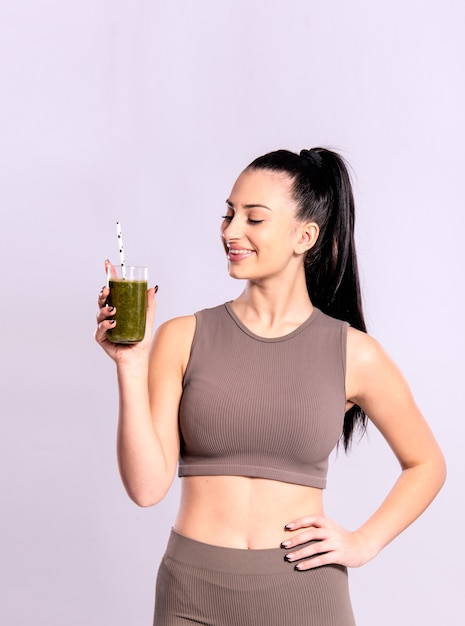 Concepto de desintoxicación, dieta saludable y fitness. Mujer joven sosteniendo un vaso con batido verde.