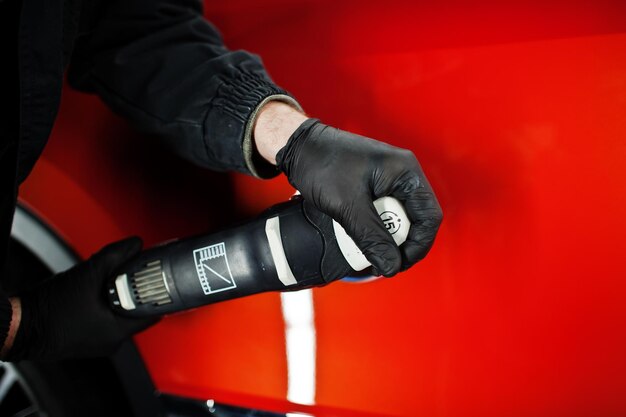 Concepto de detalle de coche Manos de hombre con pulidor orbital en taller de reparación pulido coche todoterreno naranja