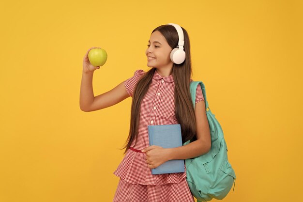 Concepto del día del conocimiento del niño de la educación en auriculares con libro y manzana para el almuerzo