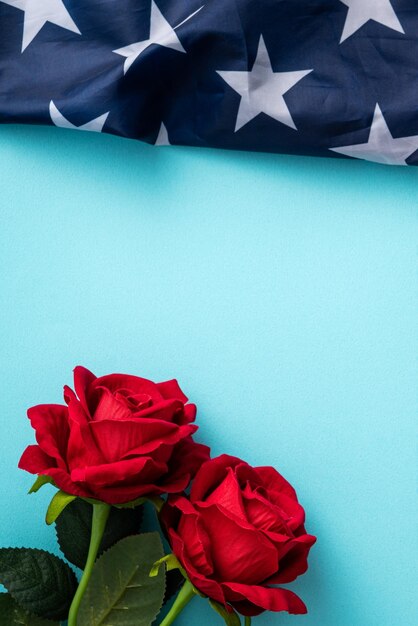 Concepto de Día de la Independencia o Día de los Caídos Bandera estadounidense sobre fondo de mesa azul con rosa roja