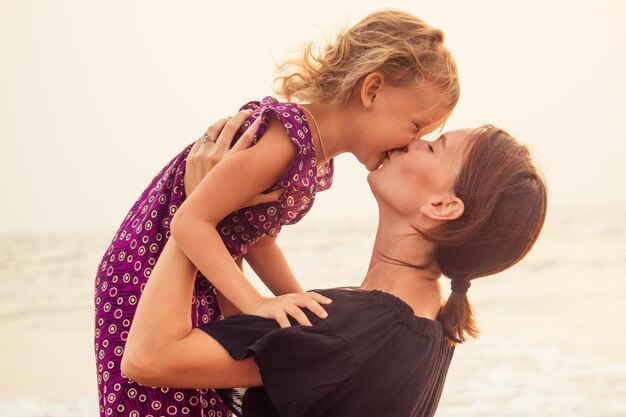 Concepto del Día de la Madre de amor, paternidad y una familia feliz. Madre e hija divirtiéndose al atardecer en la playa