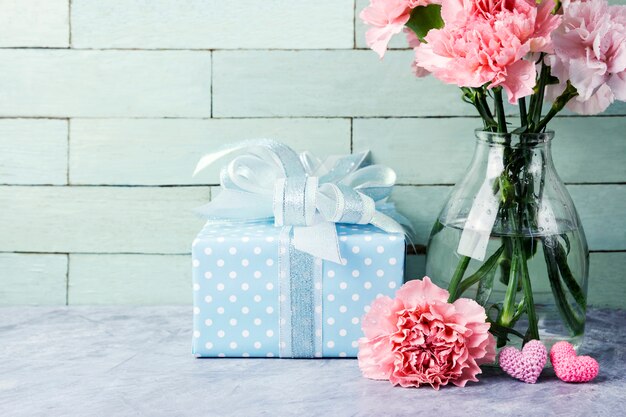 Concepto de día de las madres de flores de clavel rosa en botella transparente y caja de regalo y corazón