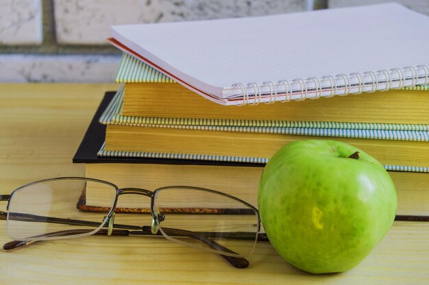 Concepto del día del maestro y regreso a la escuela Apple book verde laptop gafas de lectura y pensunlight