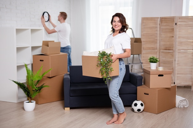 Foto concepto de día de la mudanza - retrato de la feliz pareja joven desembalaje de cajas de cartón en su nueva casa