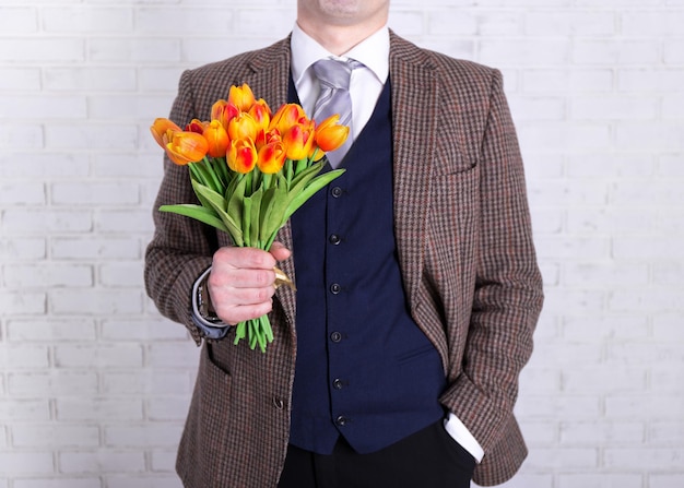 Concepto del día de la mujer o de la madre: cierre de flores en manos masculinas sobre fondo blanco