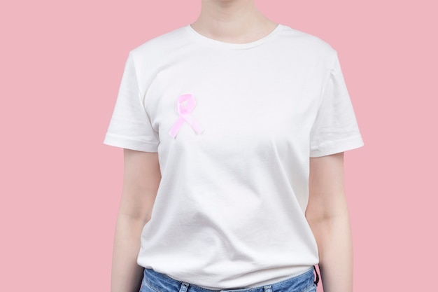 Concepto del día mundial del cáncer de mama. Mujer en camiseta blanca tiene cinta rosa en su mano. Octubre mes de concientización sobre el cáncer de mama