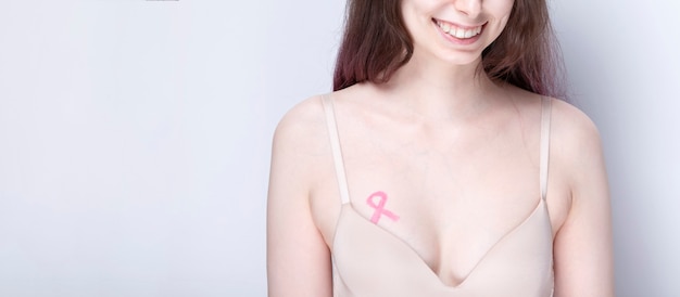 concepto del día mundial del cáncer de mama. mujer con cinta rosa pintada en el pecho