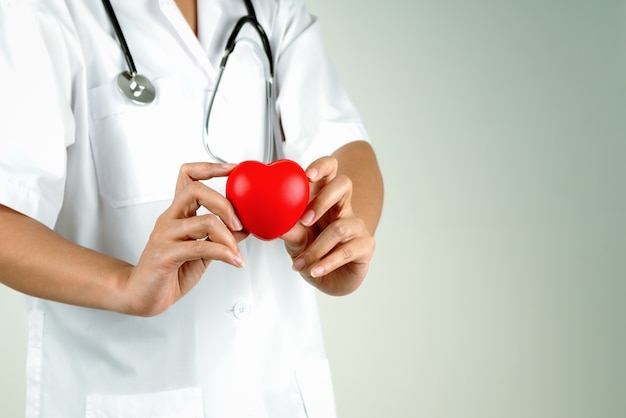 Concepto del día mundial del corazón de la mano de la doctora sosteniendo un corazón rojo