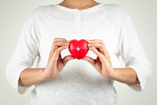 Concepto del día mundial del corazón de la mano de la mujer joven con corazón rojo