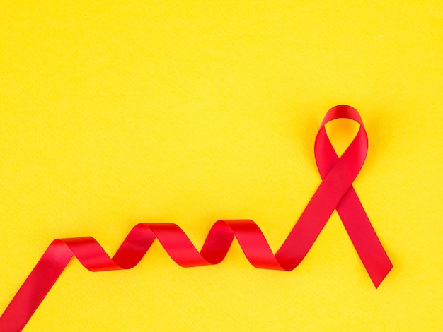 Foto concepto del día mundial del sida. cinta roja sobre fondo amarillo.