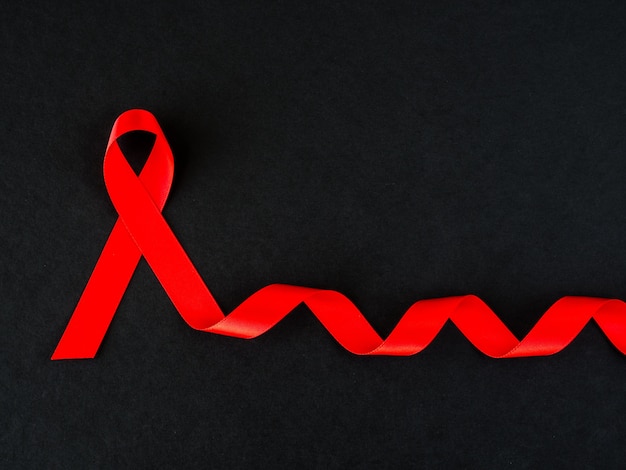 Foto concepto del día mundial del sida. cinta roja sobre fondo negro.