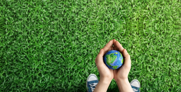 Concepto del día mundial de la tierra energía verde esg recursos renovables y sostenibles cuidado ambiental y ecológico manos de la persona que abraza el globo verde en la vista superior del parque