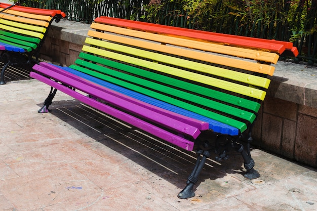Concepto del día del orgullo. Banco de madera pintado en colores del arco iris en un parque