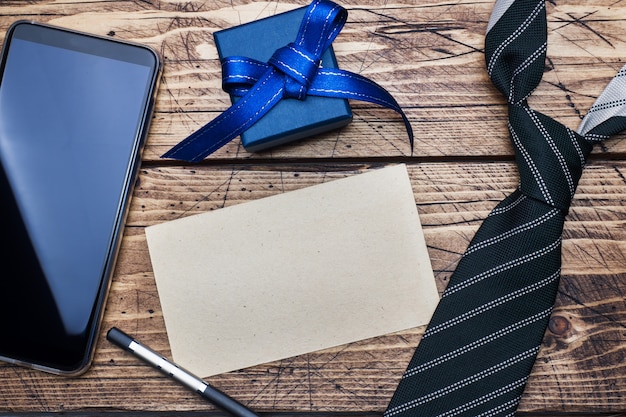 Foto concepto del día del padre. corbata a rayas, caja de regalo y teléfono y espacio para texto en mesa de madera.