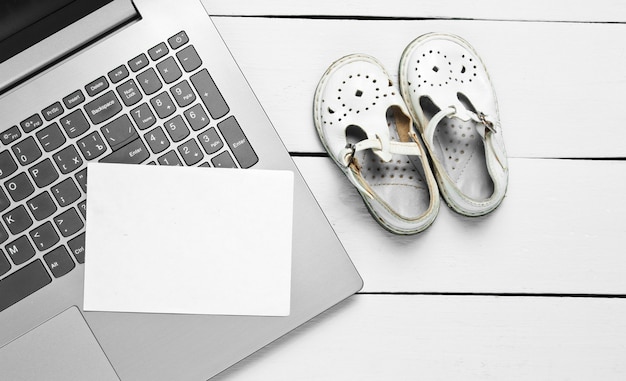 Concepto del día del padre. Ordenador portátil con papel blanco para copiar el espacio y sandalias para niños en madera