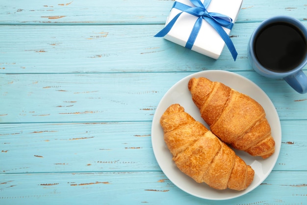 Concepto del día del padre con regalo y desayuno sobre fondo de madera azul Desayuno para papá con croissant y café