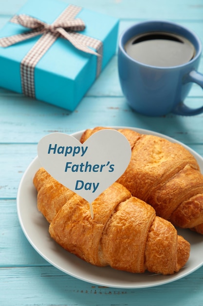 Foto concepto del día del padre con tarjeta de regalo y desayuno desayuno para papá con croissant y café