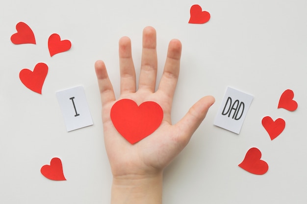 Concepto del día de padres. Mensaje con el corazón de papel en la mano de los niños en blanco