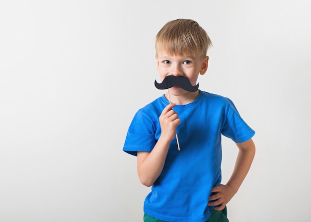 Concepto del día de padres, niña caucásica sonriendo con bigote sobre fondo blanco