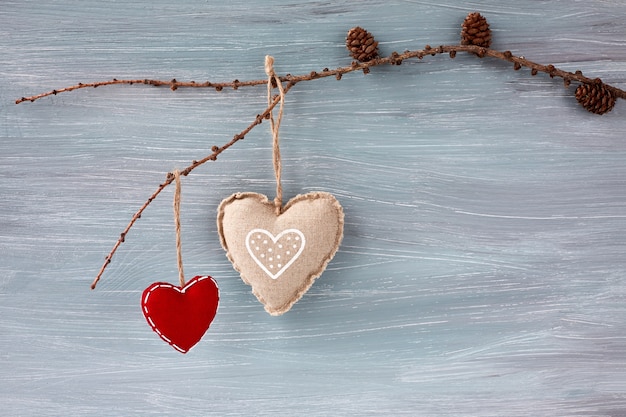 Concepto de día de San Valentín. Dos corazones que cuelgan en rama en fondo gris. Copia espacio
