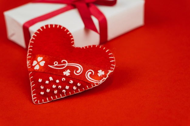 Concepto del día de San Valentín con espacio de copia Corazón textil rojo y caja goft sobre fondo de papel rojo