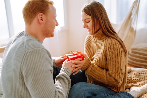 Concepto del Día de San Valentín Intercambio de regalos Pareja joven en casa celebrando el Día de San Valentín