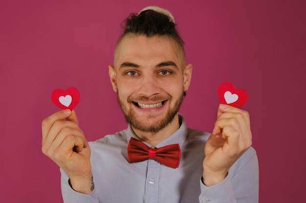 Concepto del día de San Valentín Joven hombre barbudo caucásico con rastas aislado en estudio rosa