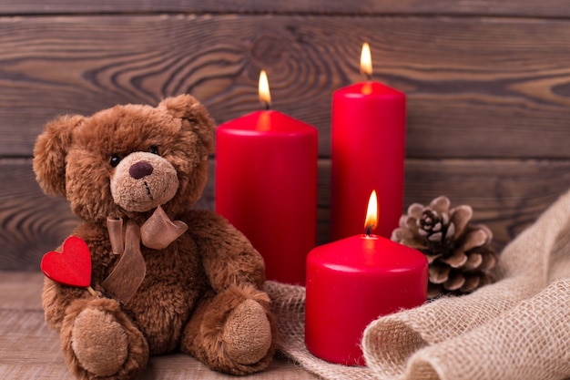 Concepto del día de San Valentín Oso de peluche mantiene las velas del corazón y un golpe sobre fondo de madera El enfoque selectivo