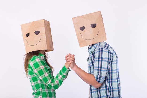 Foto concepto del día de san valentín - pareja de amor joven con bolsas sobre la cabeza sobre fondo blanco.