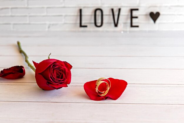 Concepto de día de san valentín rosas y anillos de boda en mesa de madera