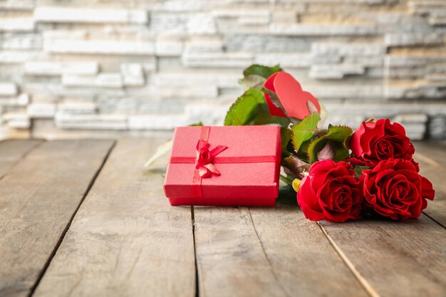 Concepto del día de San Valentín Rosas rojas frescas y caja de regalo en la mesa de madera