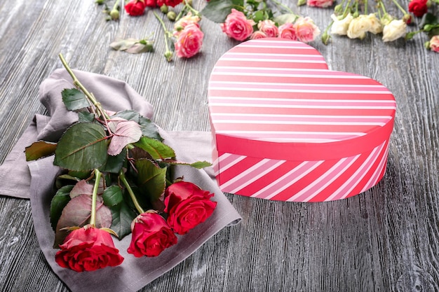 Concepto del día de San Valentín Rosas rojas frescas y caja de regalo en la mesa de madera