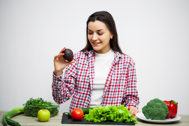 Concepto de dieta y alimentación saludable niña con verduras en el fondo de la pared blanca