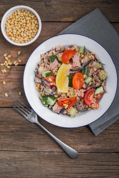 Concepto de dieta alimentaria Ensalada de atún Ensalada de cuscús con tomates de atún conservados pepinos y cebollas moradas en la mesa Espacio de copia