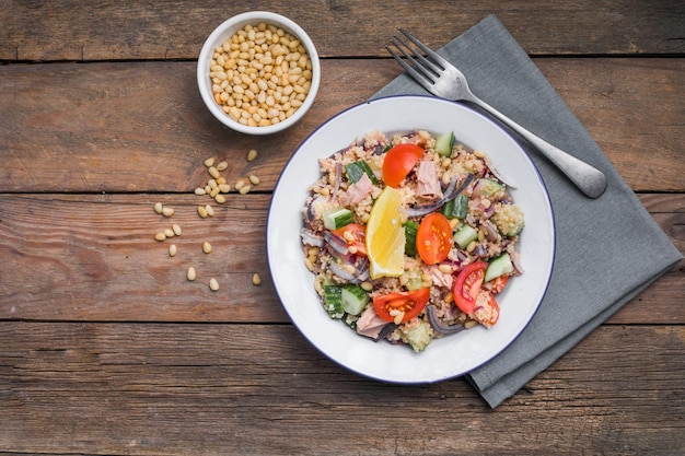 Concepto de dieta alimentaria Ensalada de atún Ensalada de cuscús con tomates de atún conservados pepinos y cebollas moradas en la mesa Espacio de copia