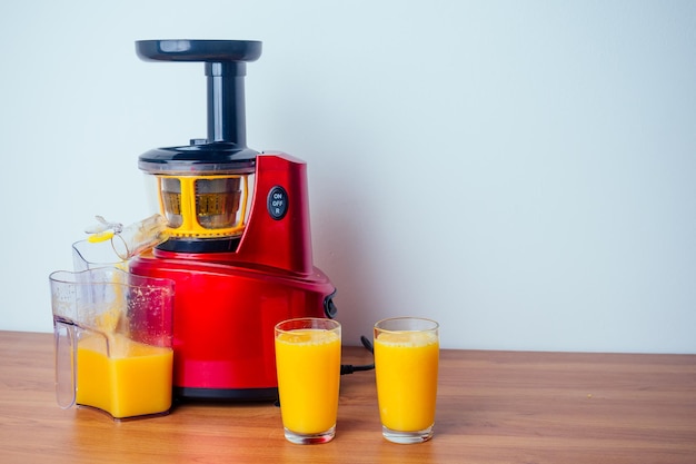 Foto concepto de dieta de alimentos crudos naranjas y máquina de jugos en fondo blanco