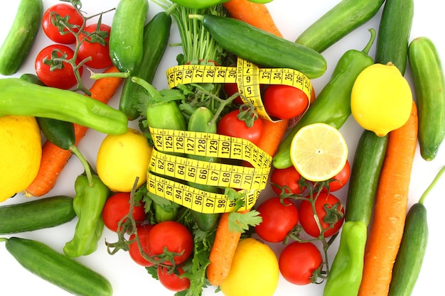 concepto de dieta con cinta métrica verduras frescas sobre un fondo blanco Enfoque selectivo