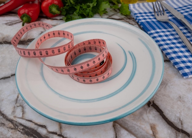 Foto concepto de dieta y deporte de alimentación saludable. un plato vacío y una cinta métrica.