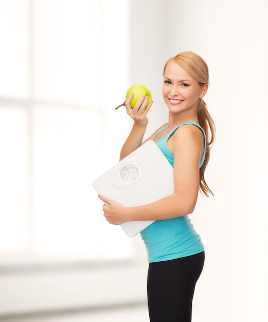 concepto de dieta, deporte y salud - hermosa mujer deportiva con escala y manzana verde