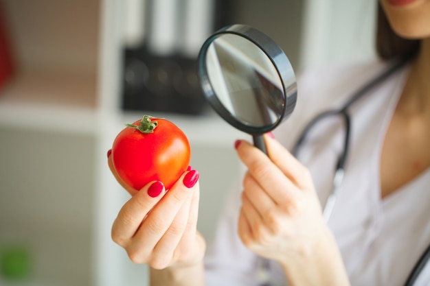Concepto de dieta Dietista inspeccionando vegetales con lupa