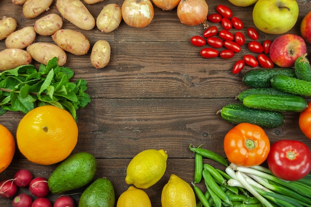 Concepto de dieta Flexitana. Composición con una variedad de verduras y frutas orgánicas frescas. Lugar para el texto. Pepinos, tomates, rábano, aguacate, guisantes, patatas, limón, cebollas. Comida sobre fondo de madera oscura.