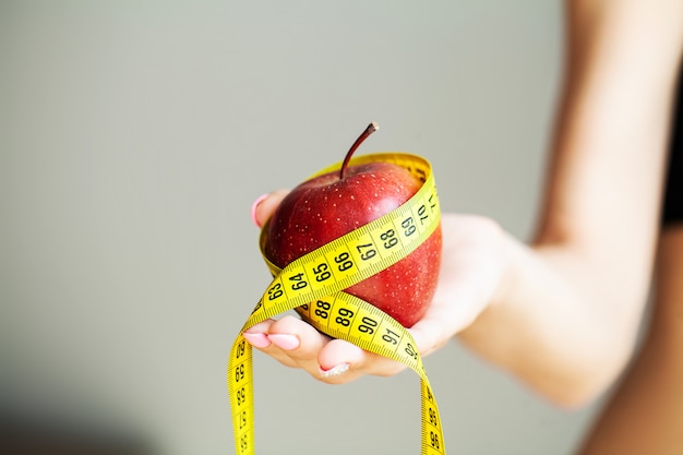 Concepto de dieta. Manzana con cinta métrica en mano femenina